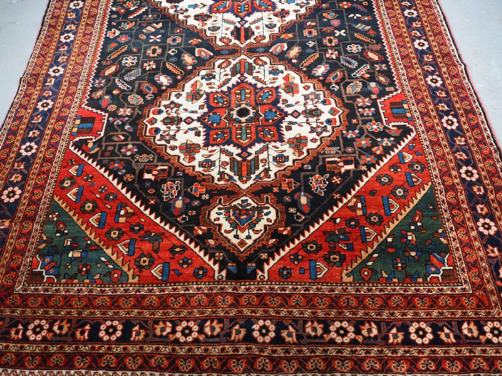 An antique hand-knotted Persian Mahal Kelleh rug featuring three ivory diamond medallions set against a navy blue field with detailed floral borders. View V
