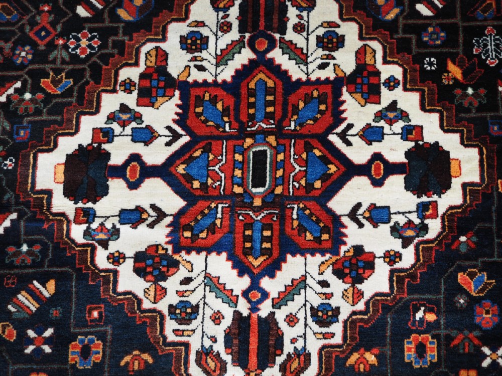 An antique hand-knotted Persian Mahal Kelleh rug featuring three ivory diamond medallions set against a navy blue field with detailed floral borders. View X