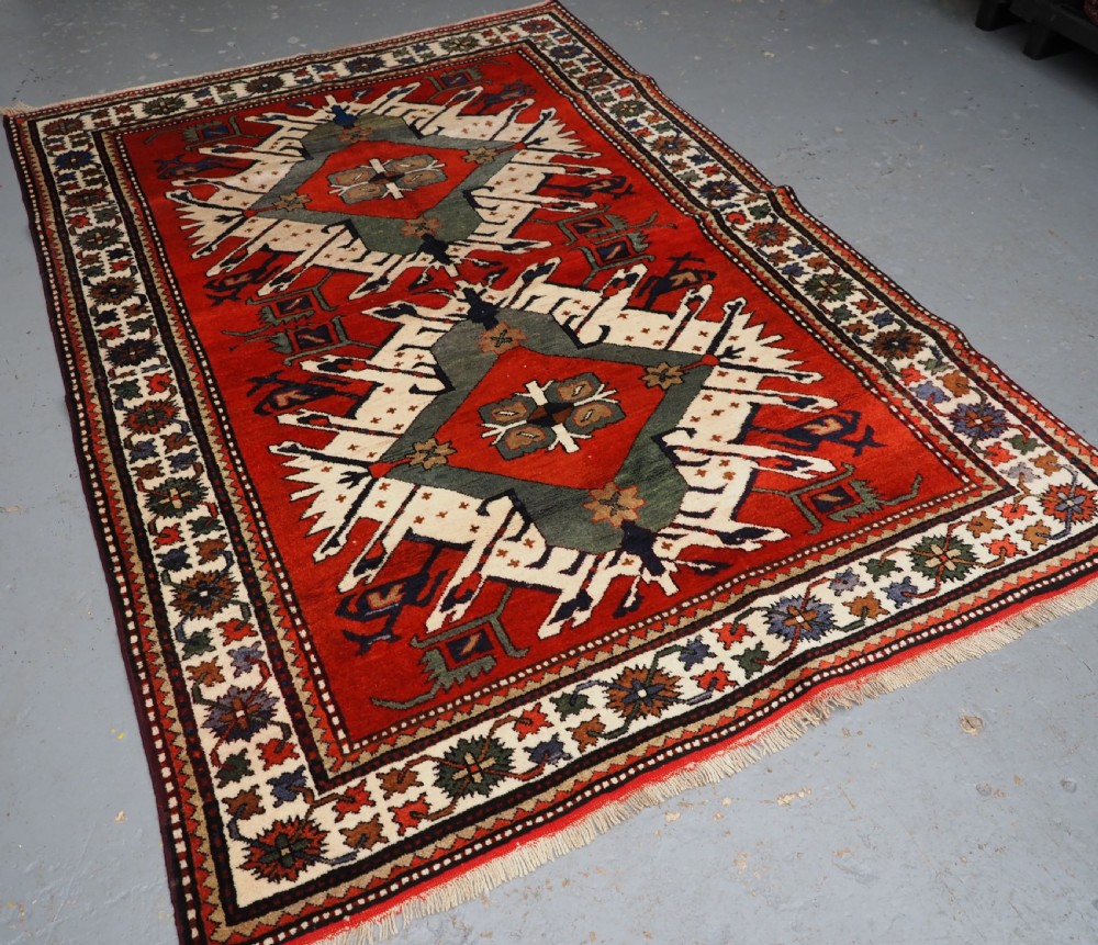 A hand-knotted Caucasian Eagle Kazak wool rug featuring radiating geometric medallions in cream, green, and navy set against a rich red central field. View II