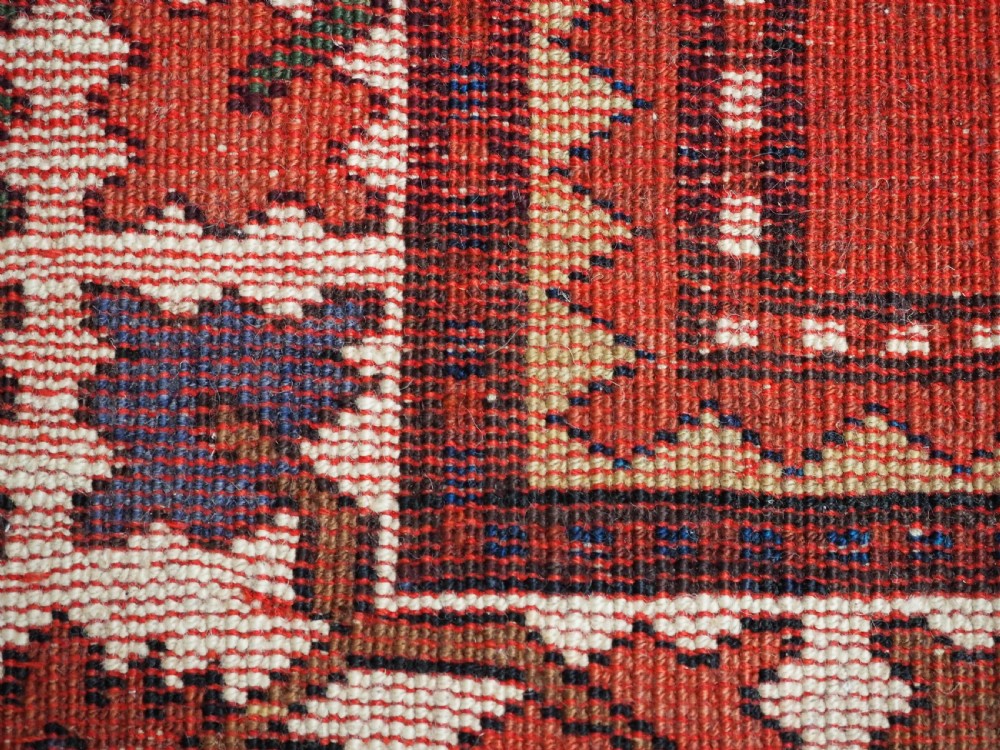 A hand-knotted Caucasian Eagle Kazak wool rug featuring radiating geometric medallions in cream, green, and navy set against a rich red central field. View XIII