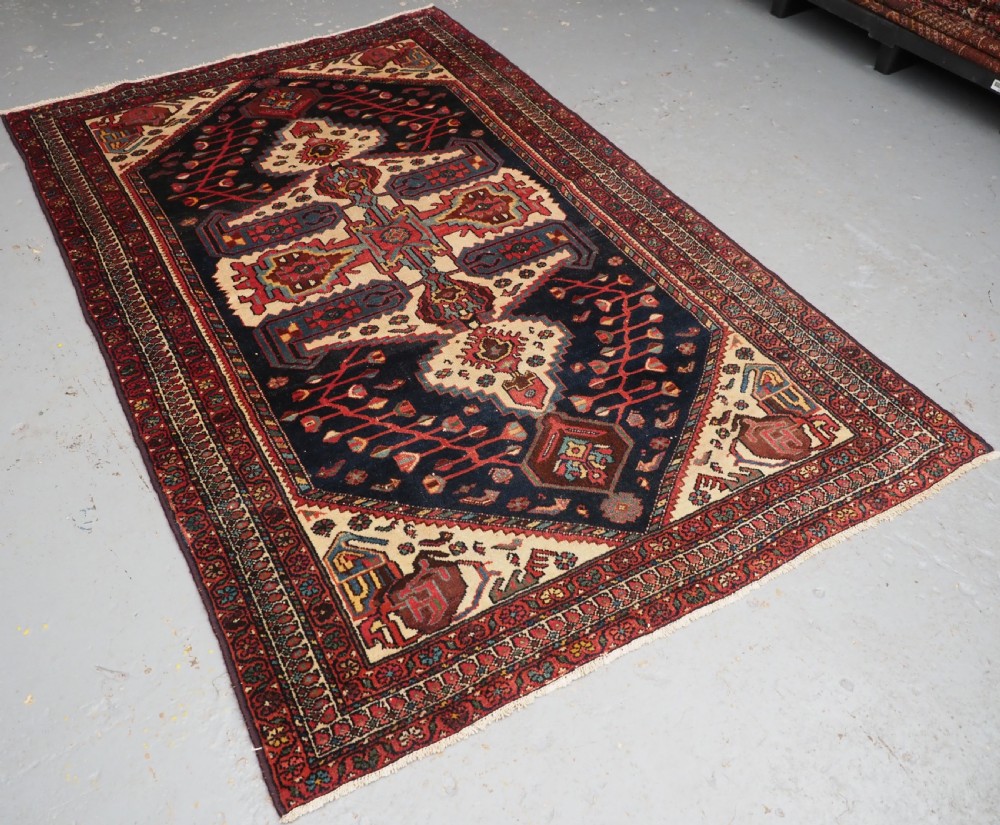An antique hand-knotted Kurdish wool rug featuring a dark navy central field with cream geometric medallions and a detailed red multi-band border. View II