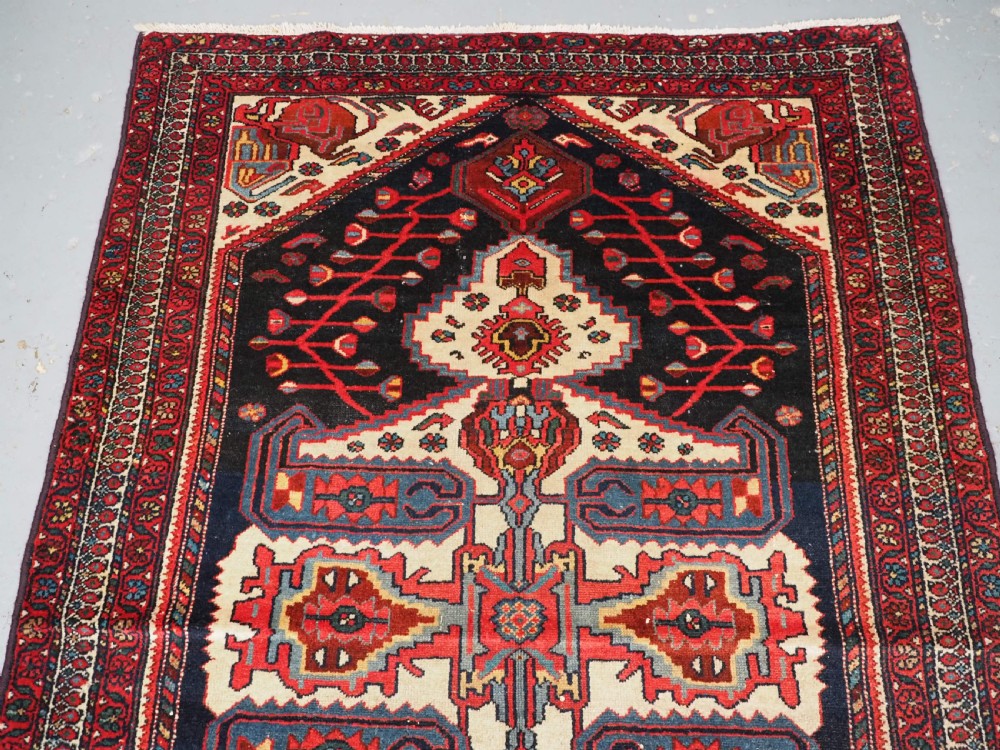 An antique hand-knotted Kurdish wool rug featuring a dark navy central field with cream geometric medallions and a detailed red multi-band border. View III