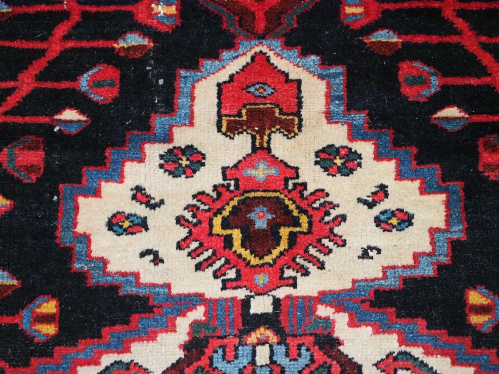 An antique hand-knotted Kurdish wool rug featuring a dark navy central field with cream geometric medallions and a detailed red multi-band border. View VIII