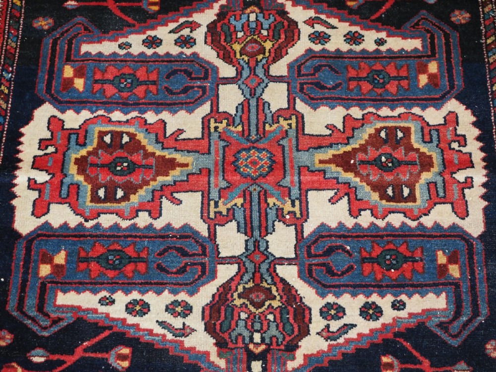 An antique hand-knotted Kurdish wool rug featuring a dark navy central field with cream geometric medallions and a detailed red multi-band border. View IX