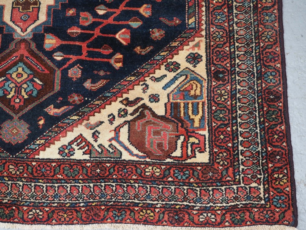 An antique hand-knotted Kurdish wool rug featuring a dark navy central field with cream geometric medallions and a detailed red multi-band border. View XI