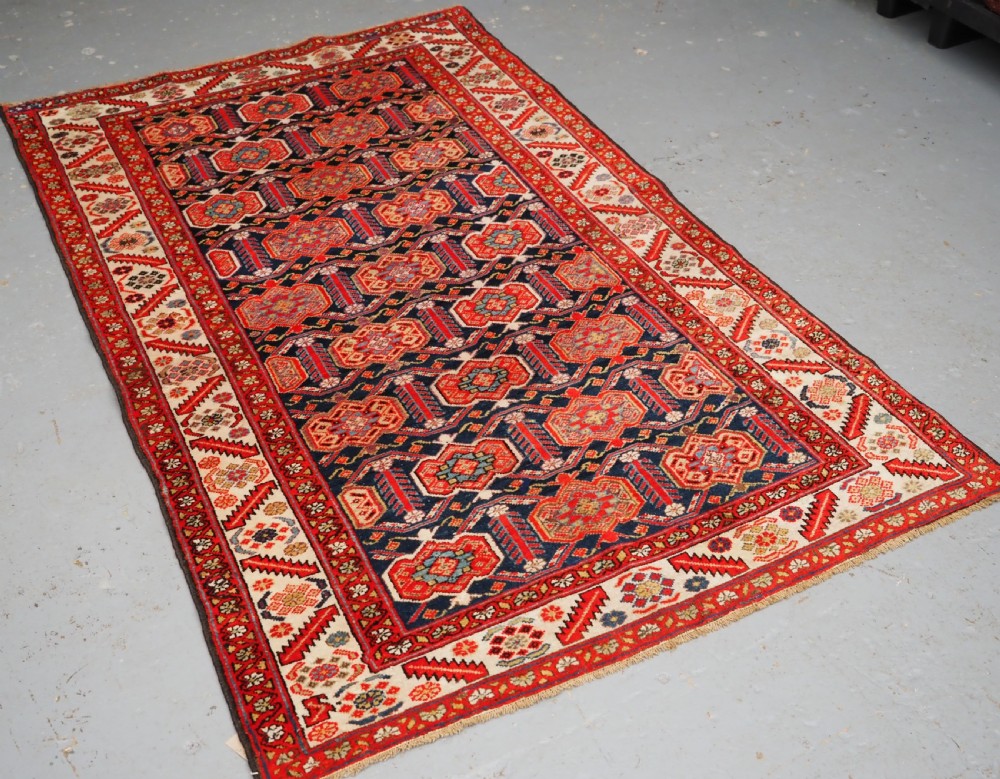 An antique hand-knotted Persian Malayer rug featuring geometric shield motifs in red, navy blue, and ivory tones. View II