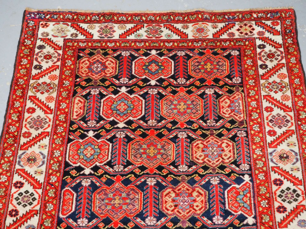 An antique hand-knotted Persian Malayer rug featuring geometric shield motifs in red, navy blue, and ivory tones. View III