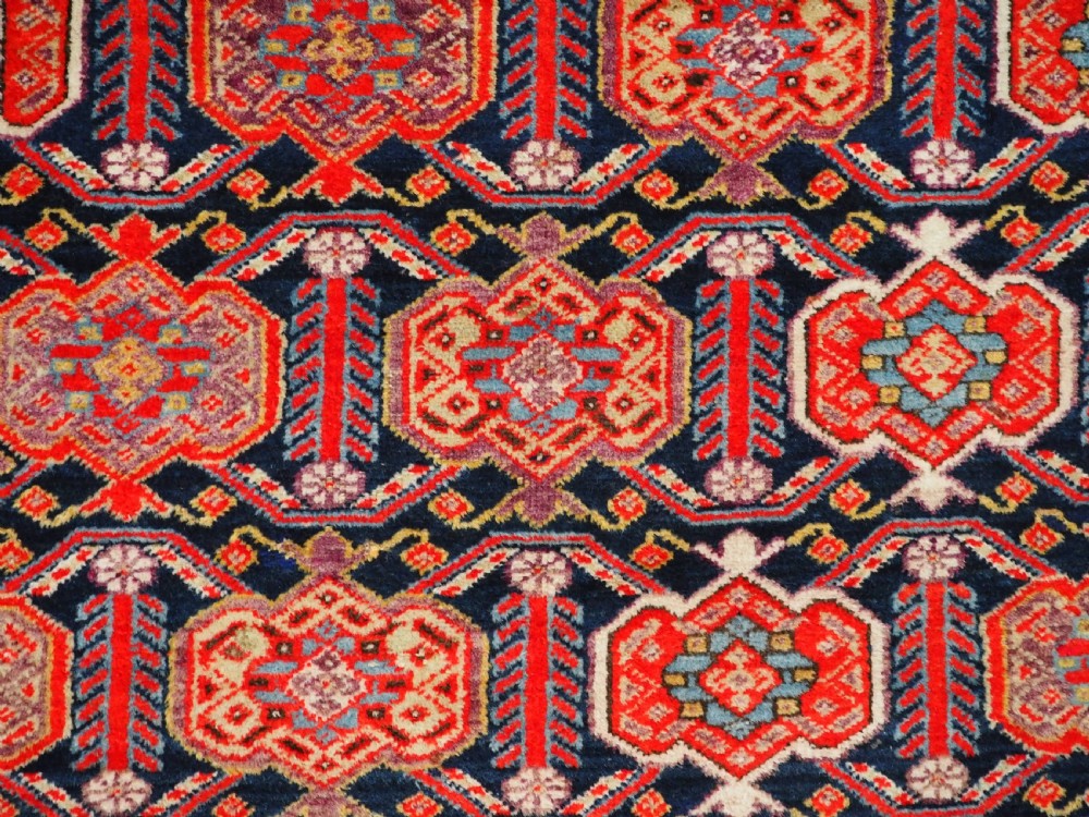An antique hand-knotted Persian Malayer rug featuring geometric shield motifs in red, navy blue, and ivory tones. View IX