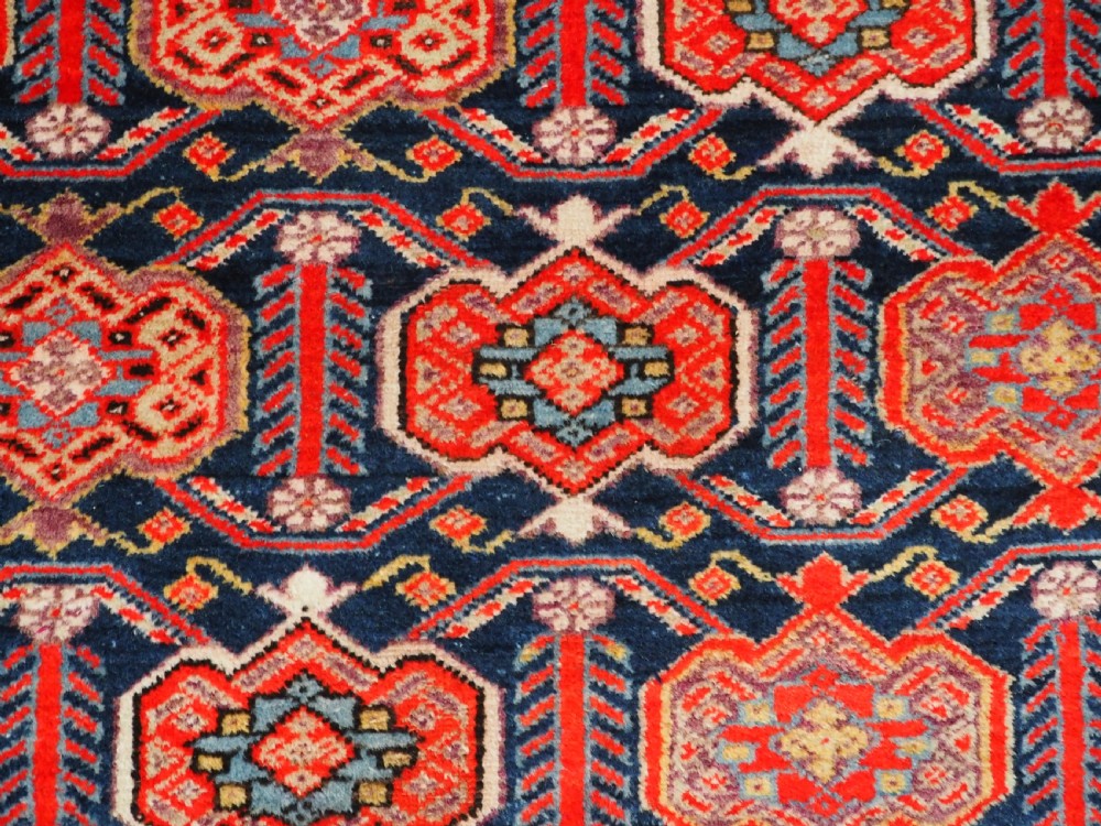 An antique hand-knotted Persian Malayer rug featuring geometric shield motifs in red, navy blue, and ivory tones. View X