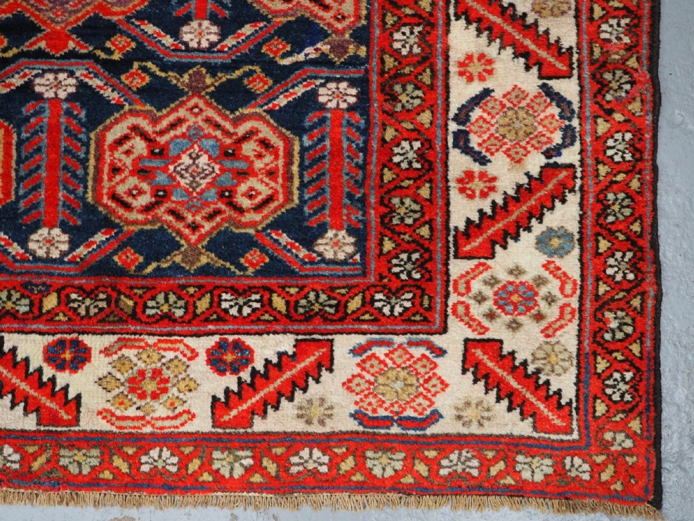 An antique hand-knotted Persian Malayer rug featuring geometric shield motifs in red, navy blue, and ivory tones. View XI