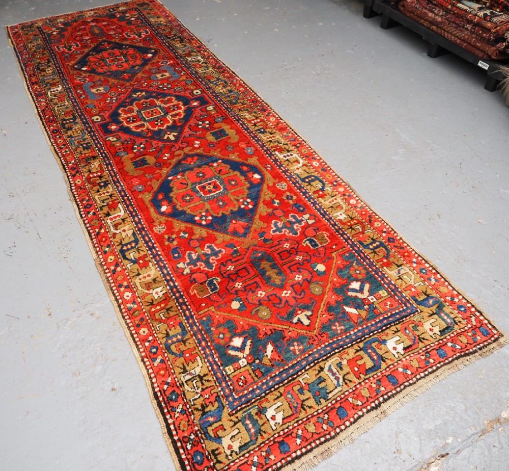A long hand-knotted Persian Heriz carpet runner featuring geometric diamond medallions in navy blue and terracotta red wool. View II