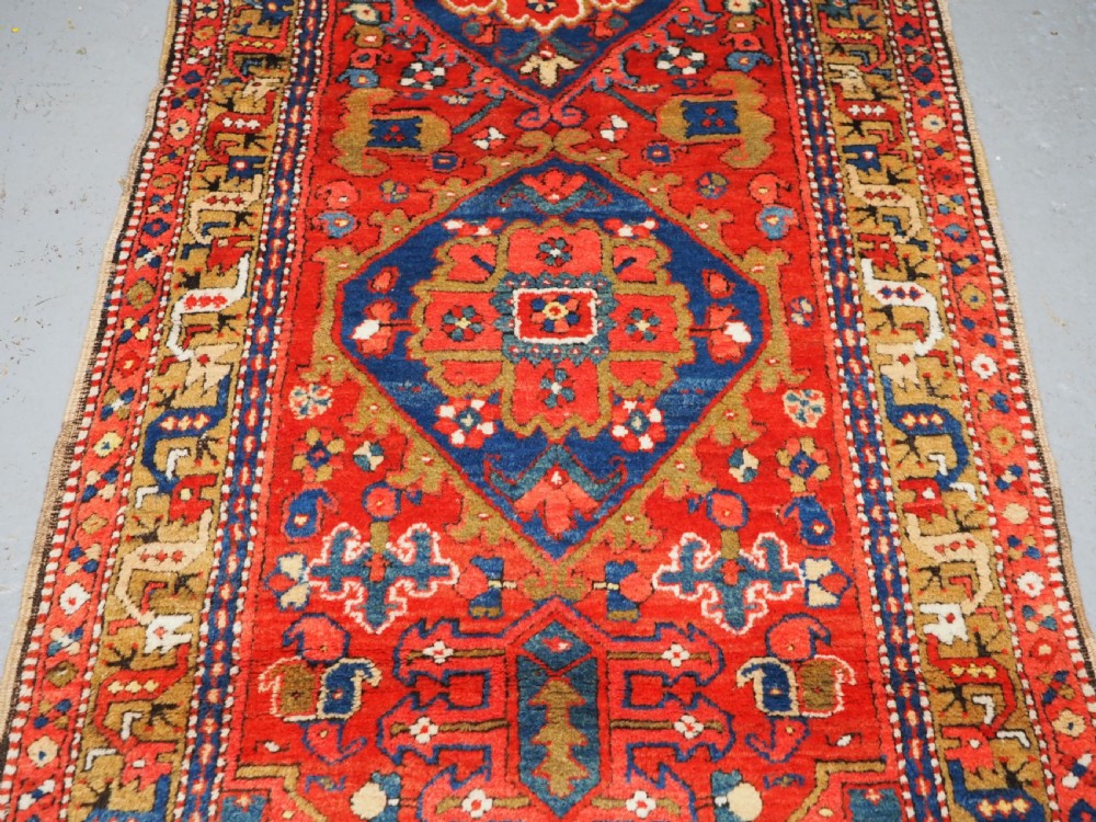 A long hand-knotted Persian Heriz carpet runner featuring geometric diamond medallions in navy blue and terracotta red wool. View VI