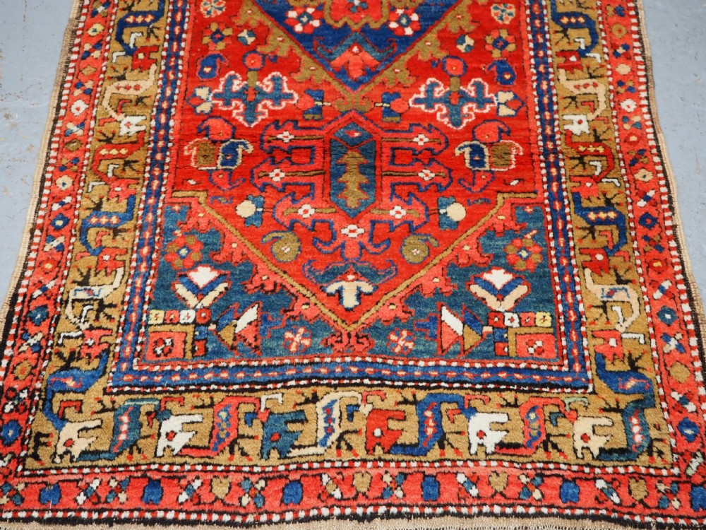 A long hand-knotted Persian Heriz carpet runner featuring geometric diamond medallions in navy blue and terracotta red wool. View VII