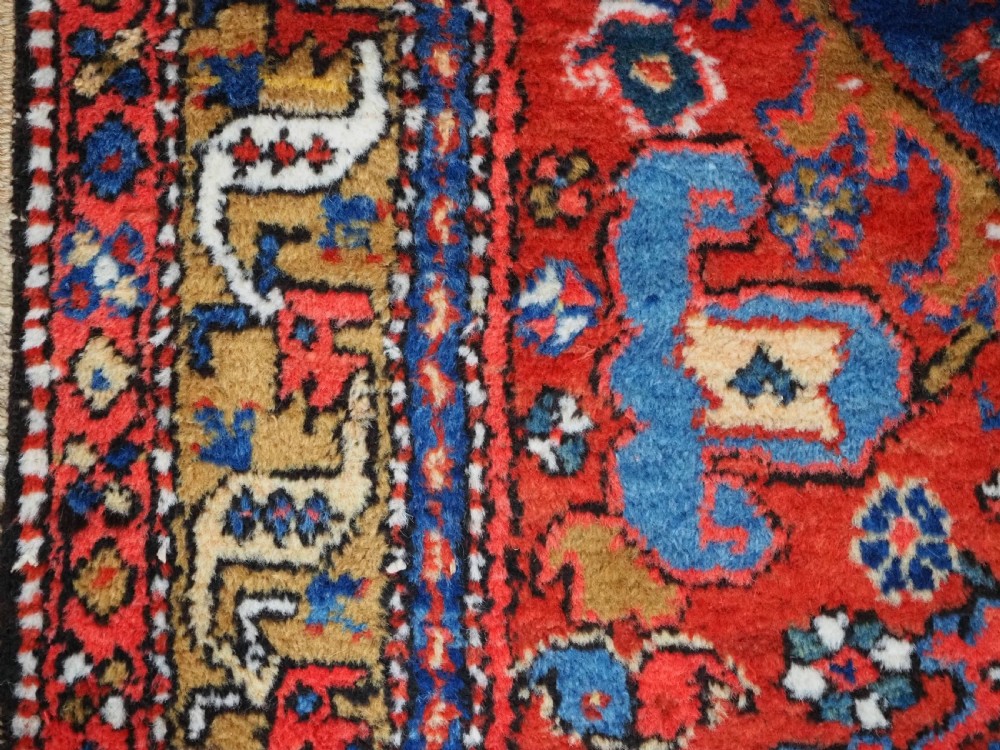 A long hand-knotted Persian Heriz carpet runner featuring geometric diamond medallions in navy blue and terracotta red wool. View IX
