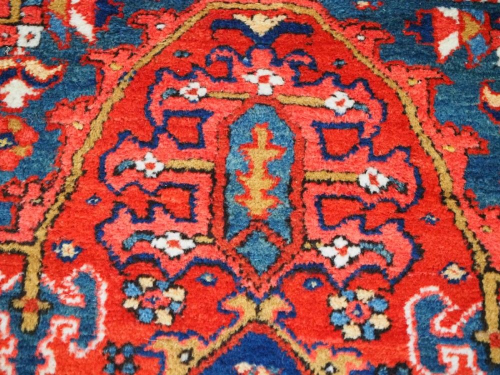 A long hand-knotted Persian Heriz carpet runner featuring geometric diamond medallions in navy blue and terracotta red wool. View X