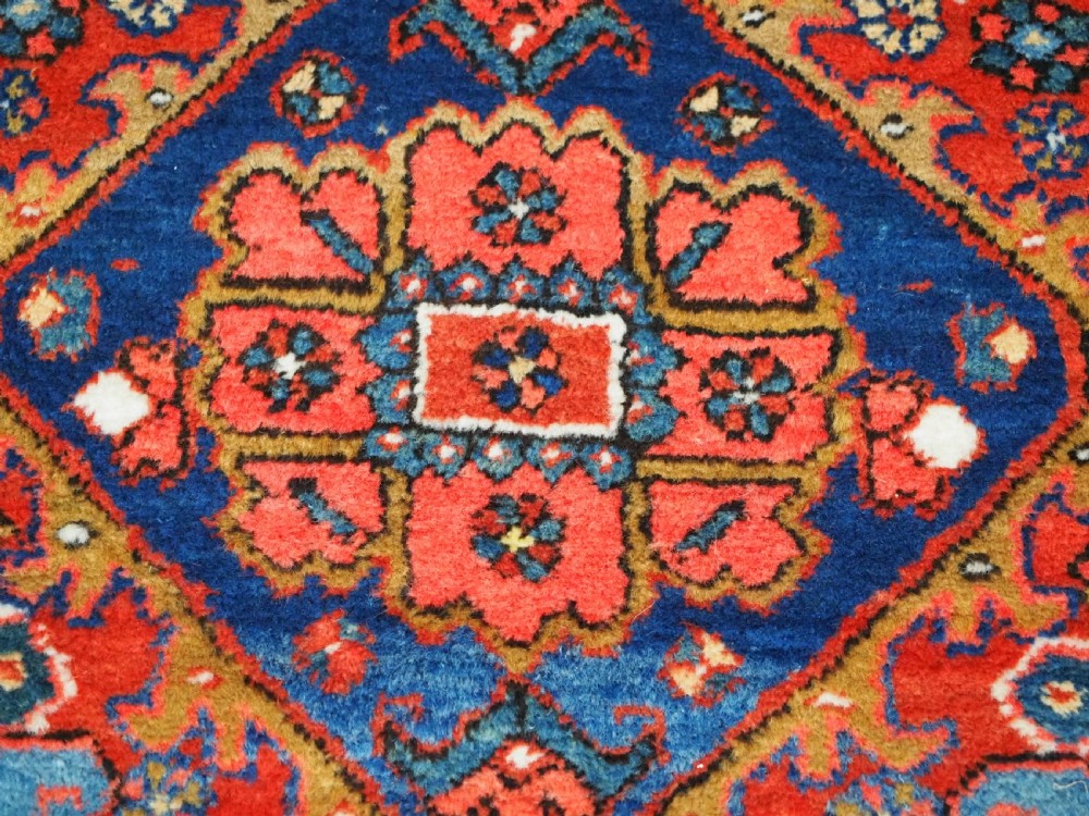 A long hand-knotted Persian Heriz carpet runner featuring geometric diamond medallions in navy blue and terracotta red wool. View XI