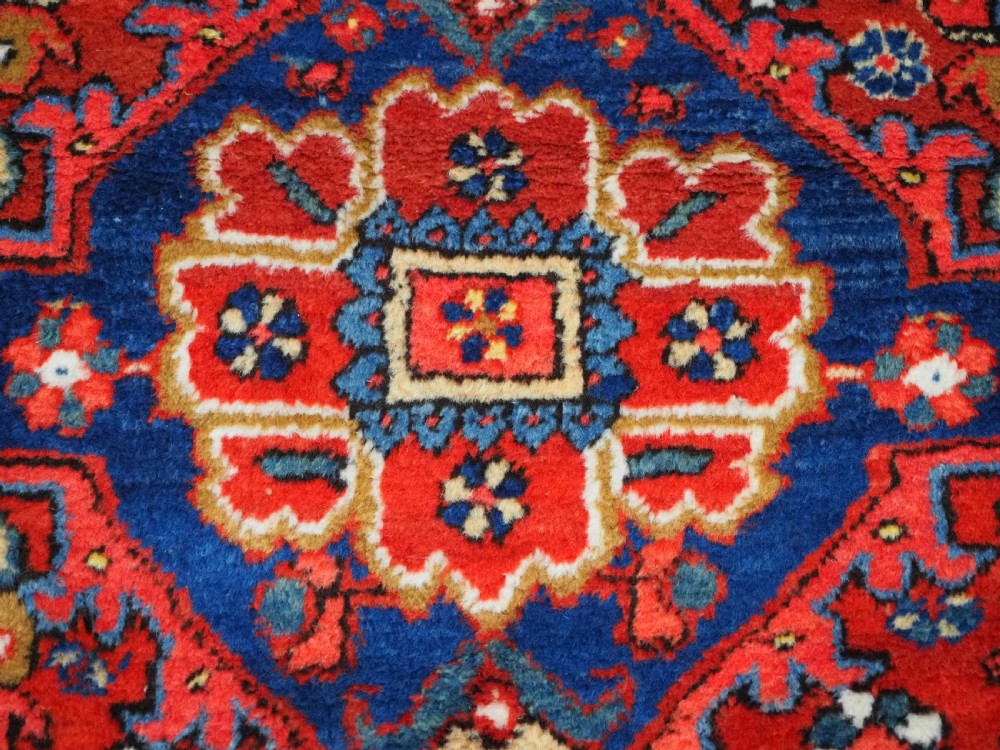 A long hand-knotted Persian Heriz carpet runner featuring geometric diamond medallions in navy blue and terracotta red wool. View XII