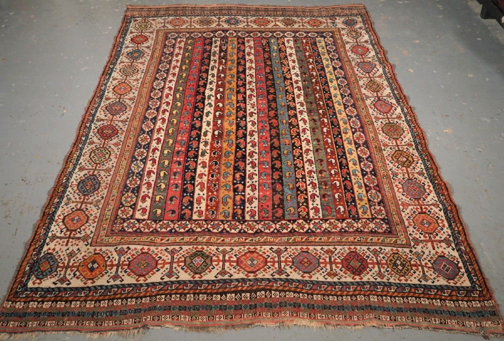 An antique hand-knotted Shekarlu Qashqai wool rug featuring vertical polychrome stripes filled with repeating boteh motifs framing a wide geometric ivory border.