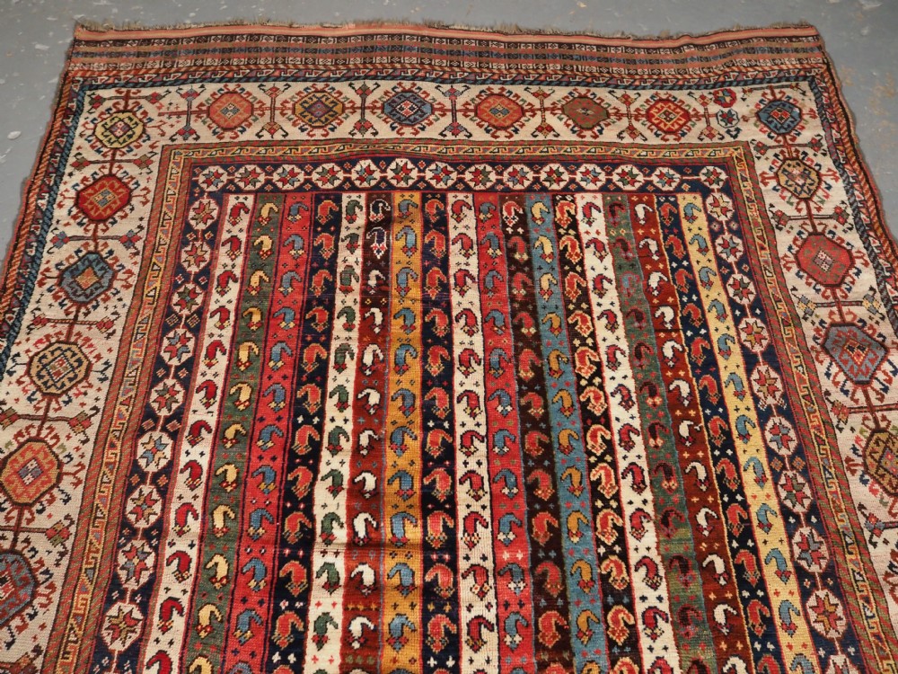 An antique hand-knotted Shekarlu Qashqai wool rug featuring vertical polychrome stripes filled with repeating boteh motifs framing a wide geometric ivory border. View III