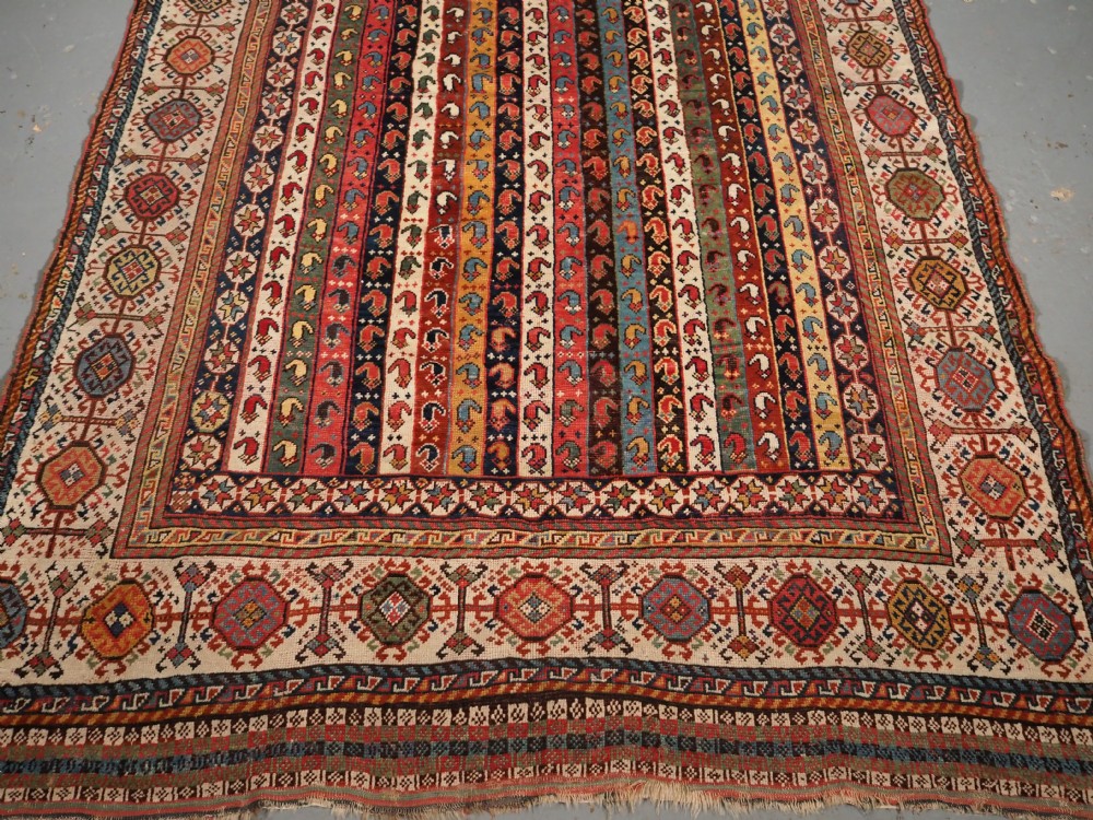 An antique hand-knotted Shekarlu Qashqai wool rug featuring vertical polychrome stripes filled with repeating boteh motifs framing a wide geometric ivory border. View V