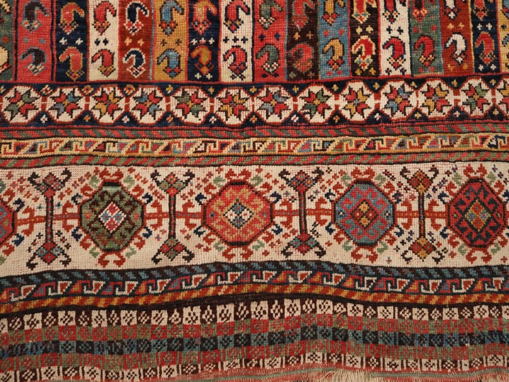 An antique hand-knotted Shekarlu Qashqai wool rug featuring vertical polychrome stripes filled with repeating boteh motifs framing a wide geometric ivory border. View XI
