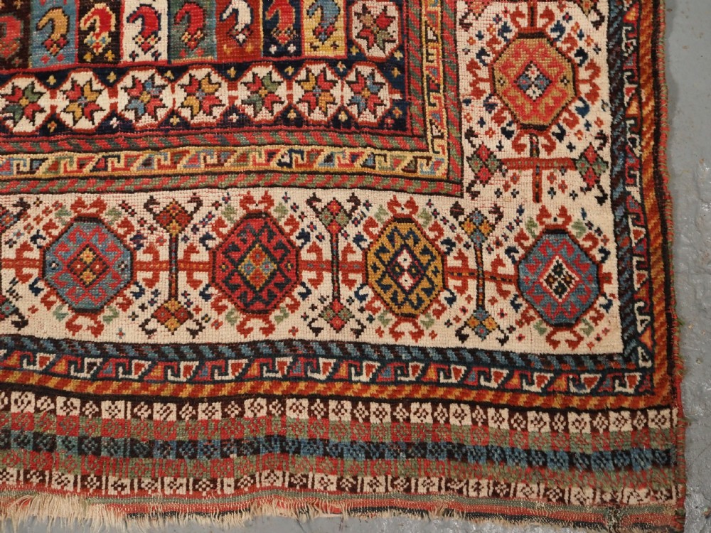 An antique hand-knotted Shekarlu Qashqai wool rug featuring vertical polychrome stripes filled with repeating boteh motifs framing a wide geometric ivory border. View XII