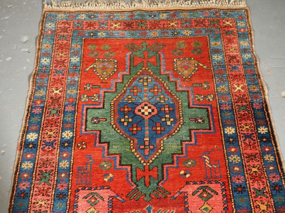 An antique hand-knotted Persian Heriz runner rug featuring geometric diamond medallions on a red ground with green, blue, and yellow accents. View III