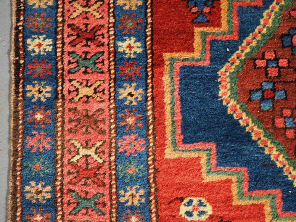 An antique hand-knotted Persian Heriz runner rug featuring geometric diamond medallions on a red ground with green, blue, and yellow accents. View VII