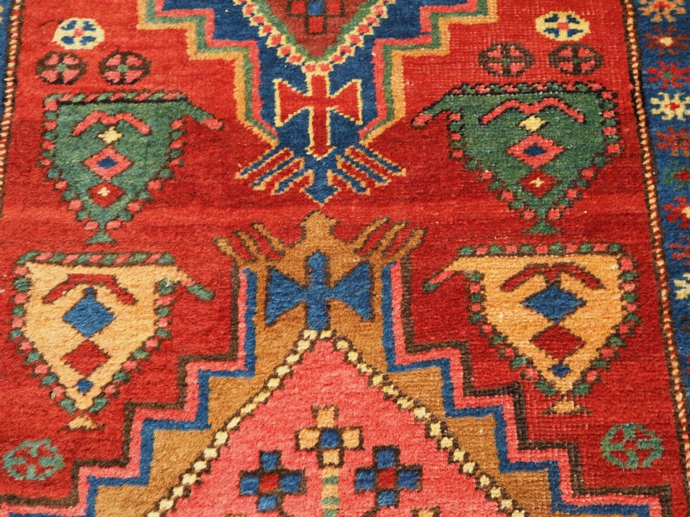 An antique hand-knotted Persian Heriz runner rug featuring geometric diamond medallions on a red ground with green, blue, and yellow accents. View VIII