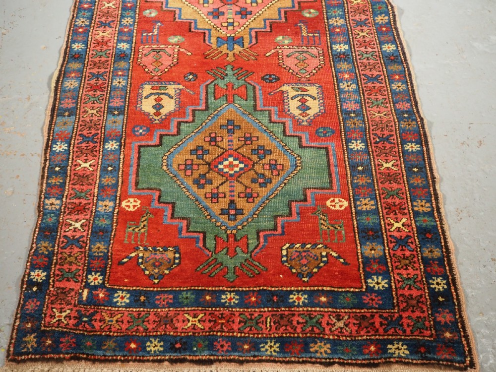 An antique hand-knotted Persian Heriz runner rug featuring geometric diamond medallions on a red ground with green, blue, and yellow accents. View XII