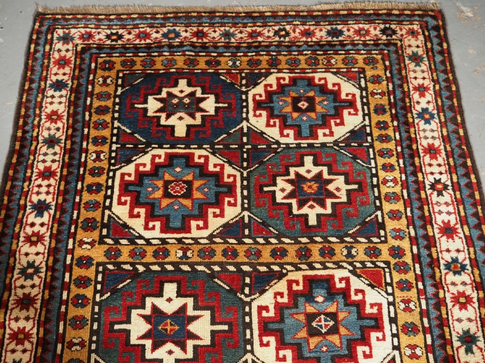 An antique Caucasian Moghan Kazak long wool rug featuring a repeating pattern of geometric Memling guls framed by intricate multi-band borders. View III