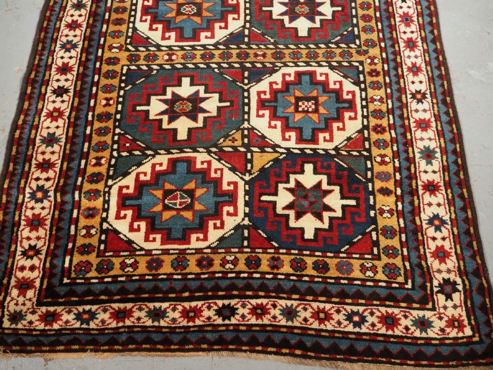 An antique Caucasian Moghan Kazak long wool rug featuring a repeating pattern of geometric Memling guls framed by intricate multi-band borders. View VI