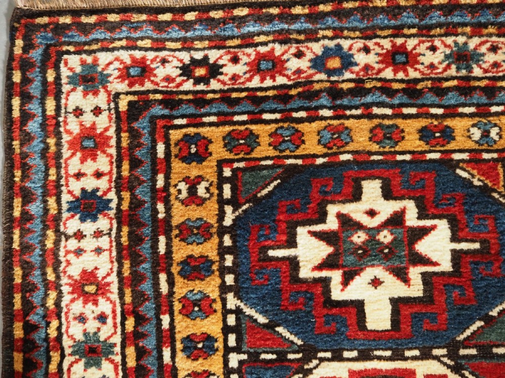 An antique Caucasian Moghan Kazak long wool rug featuring a repeating pattern of geometric Memling guls framed by intricate multi-band borders. View VII