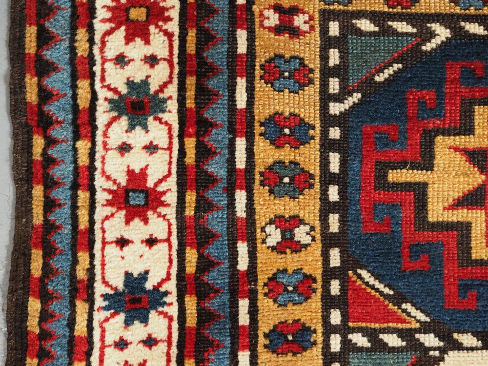 An antique Caucasian Moghan Kazak long wool rug featuring a repeating pattern of geometric Memling guls framed by intricate multi-band borders. View VIII