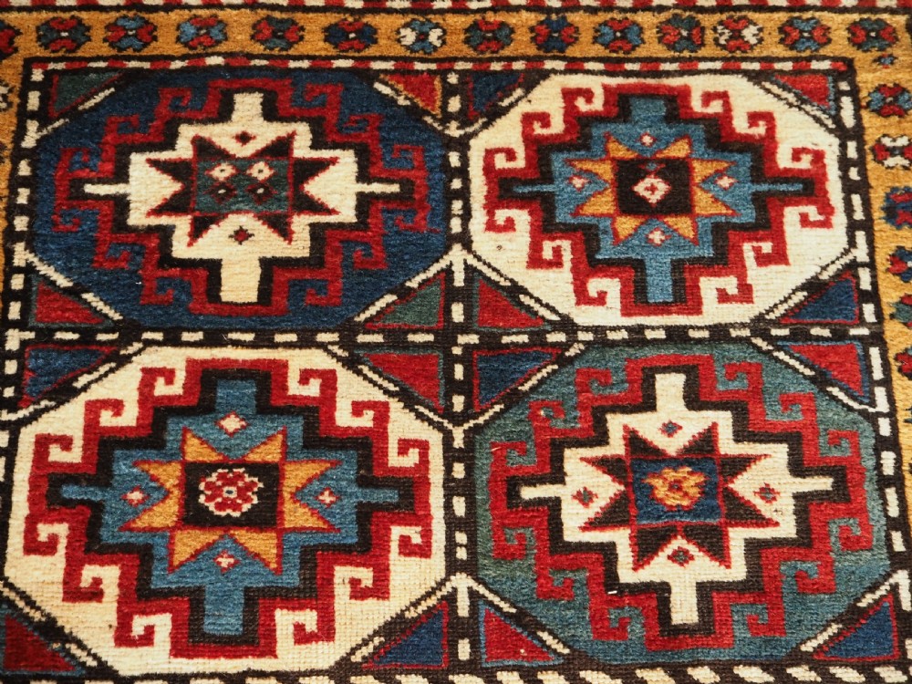 An antique Caucasian Moghan Kazak long wool rug featuring a repeating pattern of geometric Memling guls framed by intricate multi-band borders. View IX