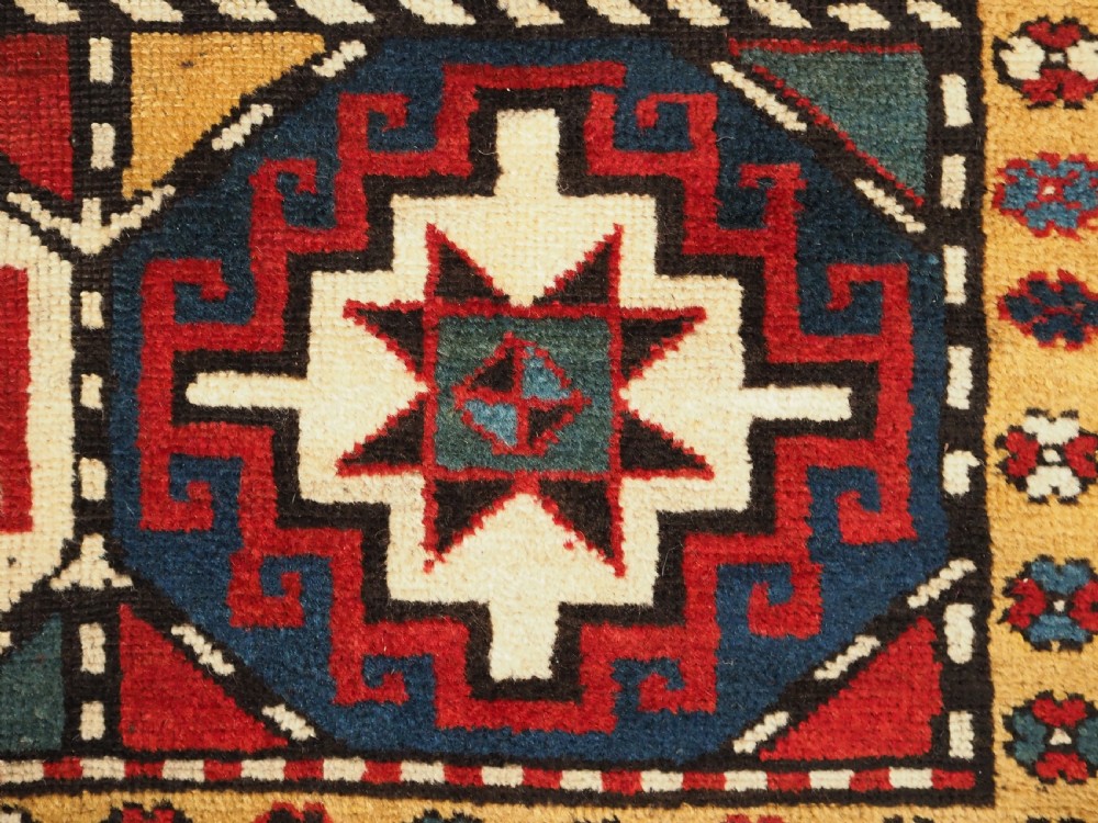 An antique Caucasian Moghan Kazak long wool rug featuring a repeating pattern of geometric Memling guls framed by intricate multi-band borders. View XI
