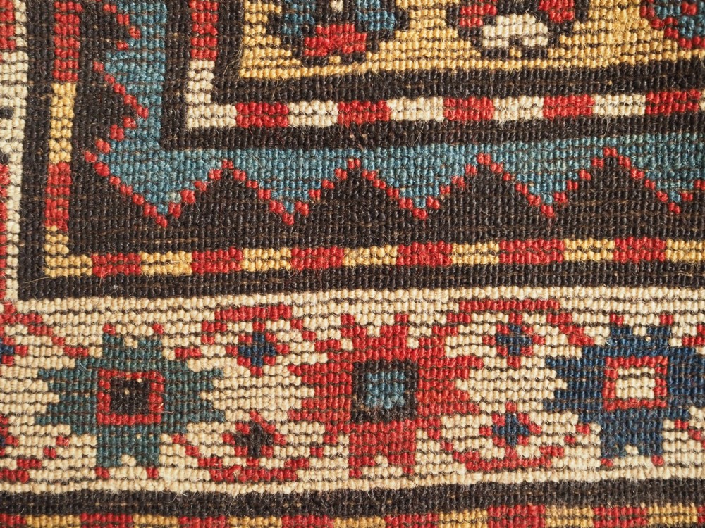 An antique Caucasian Moghan Kazak long wool rug featuring a repeating pattern of geometric Memling guls framed by intricate multi-band borders. View XII