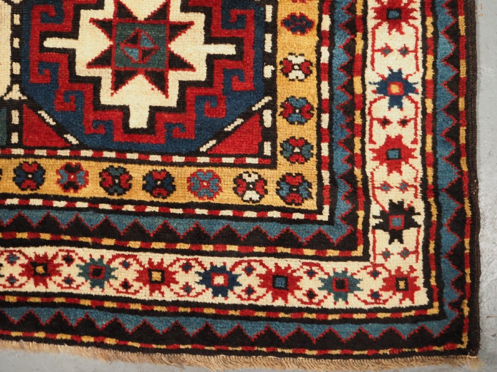 An antique Caucasian Moghan Kazak long wool rug featuring a repeating pattern of geometric Memling guls framed by intricate multi-band borders. View XIII