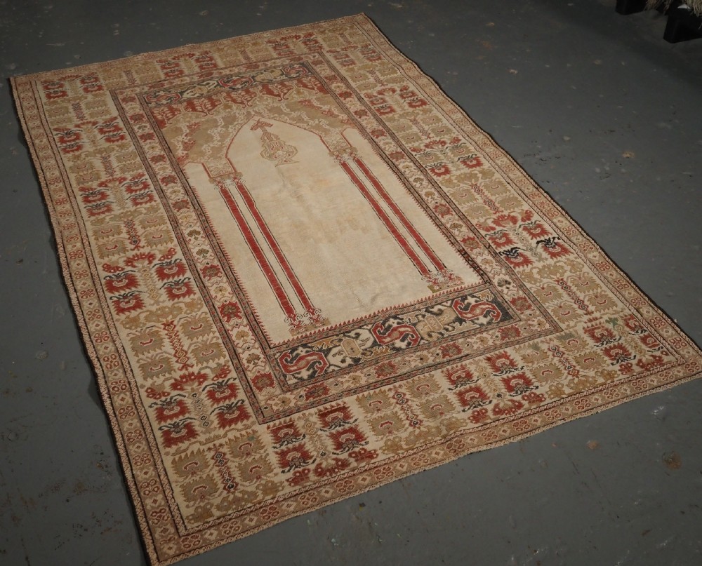 An 18th-century Turkish Ghiordes prayer rug featuring a cream central mihrab arch framed by red columns and ornate floral borders. View II