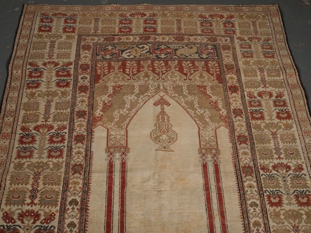 An 18th-century Turkish Ghiordes prayer rug featuring a cream central mihrab arch framed by red columns and ornate floral borders. View III