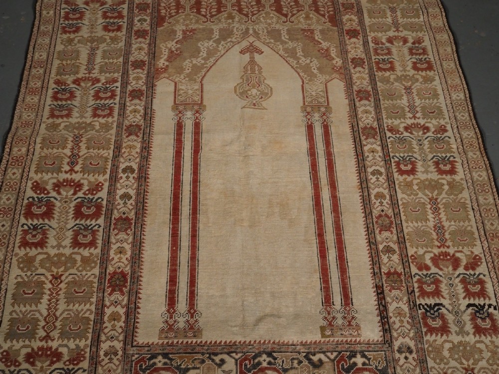An 18th-century Turkish Ghiordes prayer rug featuring a cream central mihrab arch framed by red columns and ornate floral borders. View IV