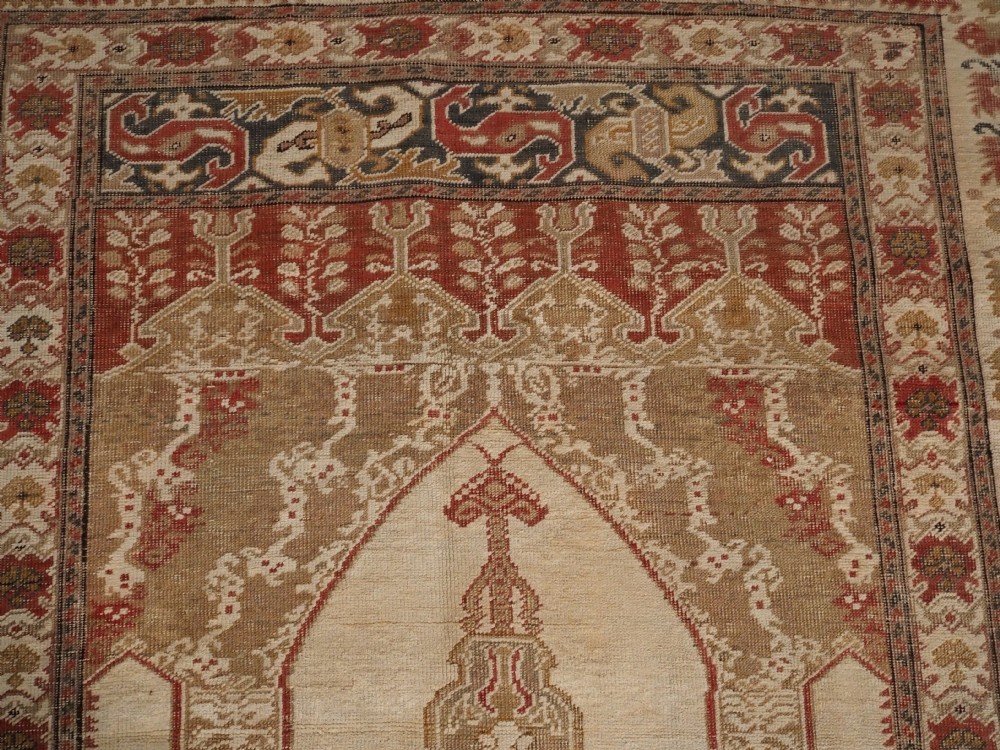 An 18th-century Turkish Ghiordes prayer rug featuring a cream central mihrab arch framed by red columns and ornate floral borders. View VII