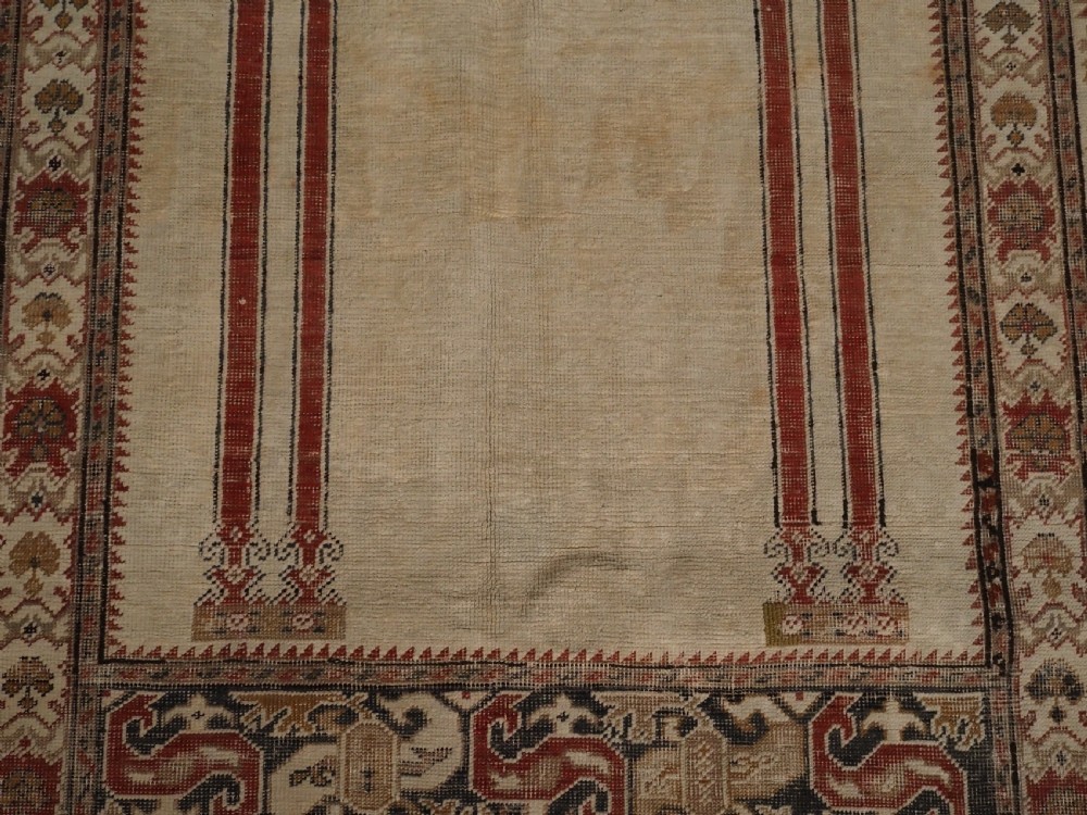 An 18th-century Turkish Ghiordes prayer rug featuring a cream central mihrab arch framed by red columns and ornate floral borders. View VIII