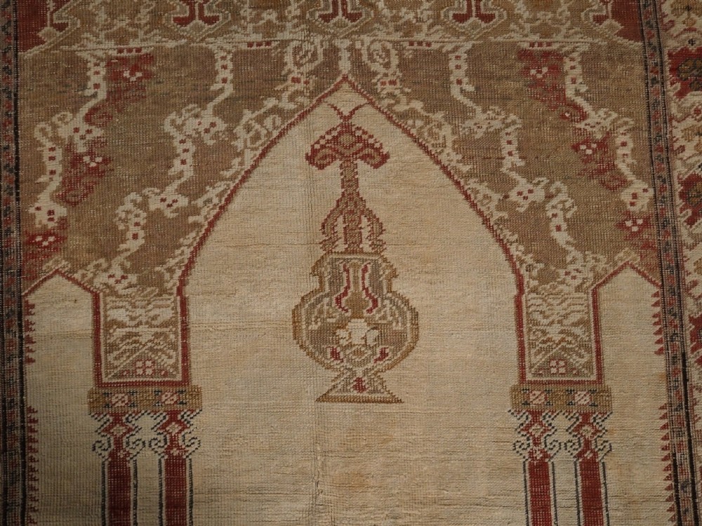 An 18th-century Turkish Ghiordes prayer rug featuring a cream central mihrab arch framed by red columns and ornate floral borders. View IX