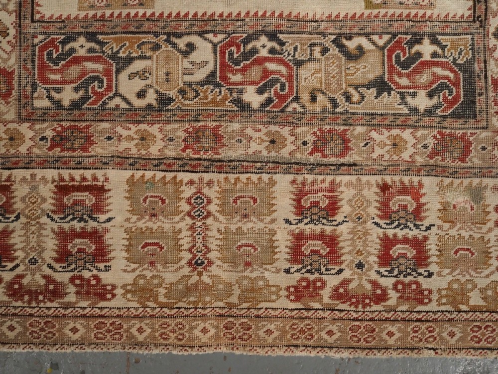An 18th-century Turkish Ghiordes prayer rug featuring a cream central mihrab arch framed by red columns and ornate floral borders. View X