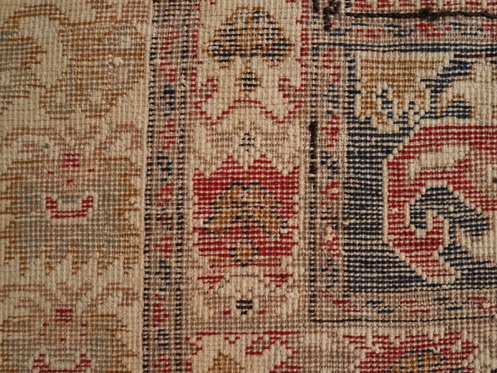 An 18th-century Turkish Ghiordes prayer rug featuring a cream central mihrab arch framed by red columns and ornate floral borders. View XII