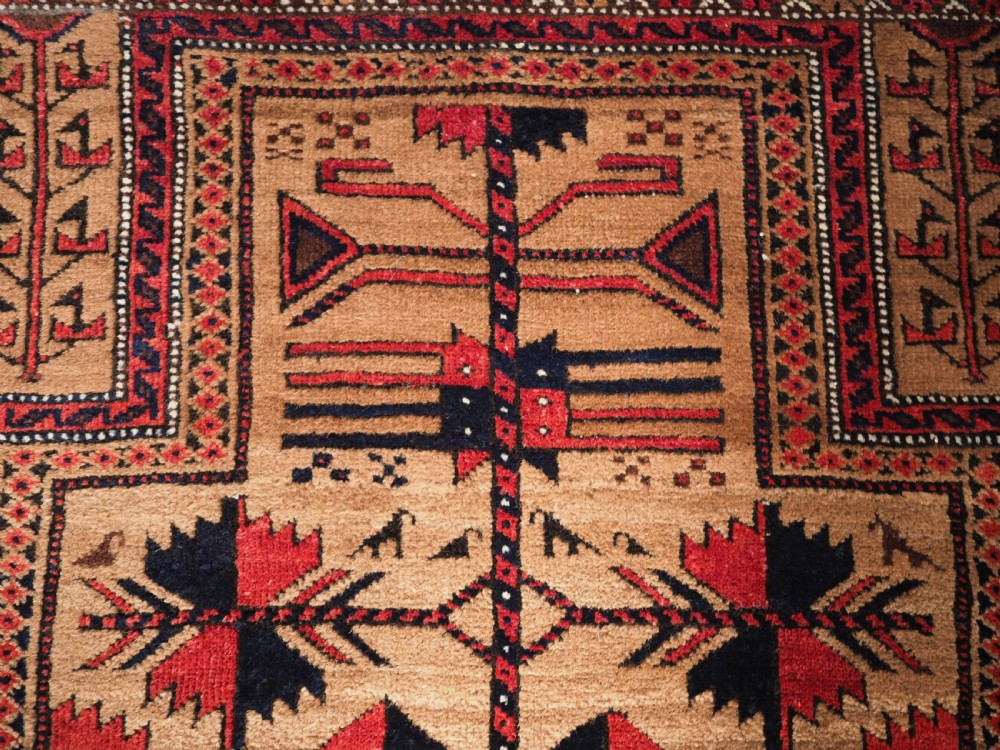 An antique Baluch wool rug featuring a central Tree of Life motif on a camel-coloured ground, framed by geometric red and black patterned borders. View VI