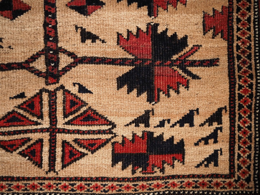 An antique Baluch wool rug featuring a central Tree of Life motif on a camel-coloured ground, framed by geometric red and black patterned borders. View VIII