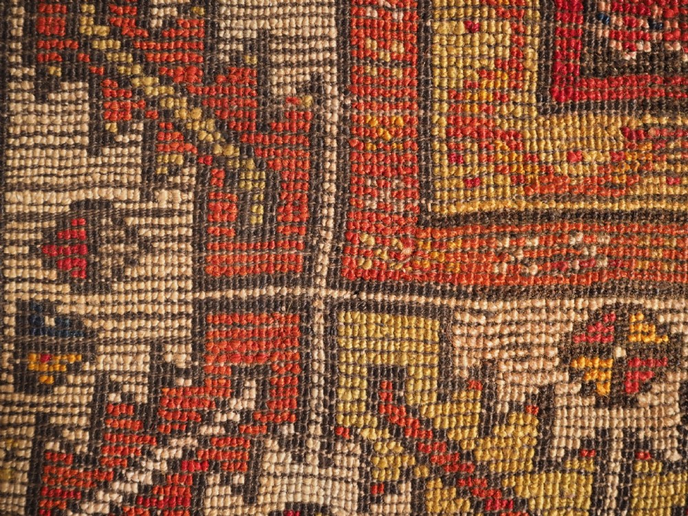 An antique hand-knotted Turkish Konya prayer rug featuring a deep red central stepped mihrab arch bordered by geometric motifs in navy blue, ochre, and cream. View IX