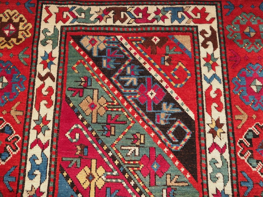 An antique Caucasian Gendje Kazak hand-knotted wool rug featuring diagonal polychrome stripes within a wide geometric border on a red field. View VII